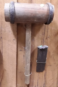 A large handmade wooden maul and wedge used to split timber.
