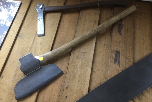 A forged steel metal headed axe with a turned wooden handle