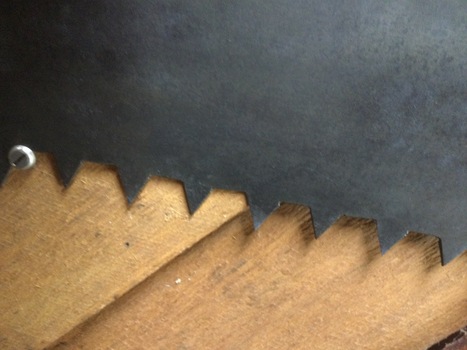 A steel peg toothed crosscut saw with wooden handles bolted on.