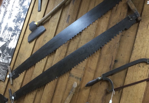 A forged steel peg  toothed crosscut saw with wooden handles bolted on. 