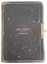 A small faded black covered Holy Bible with a damaged brass hinge.