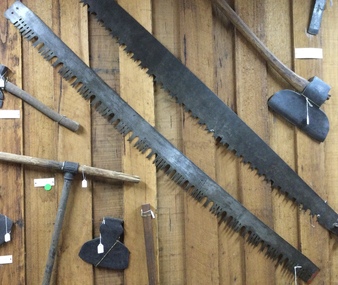 A steel “M” toothed crosscut saw with wooden handles. 