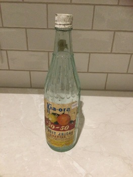 Pale green glass bottle, Kia-ora 50 - 50 Fruit Juice Cordial with white, metal, screw-on lid. 