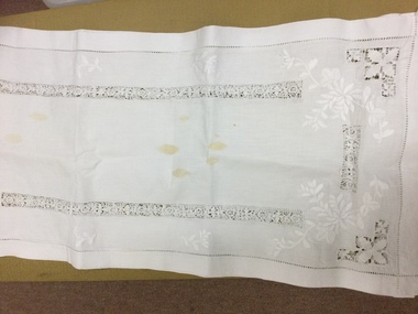 Badly stained and worn table runner.