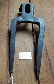 A two pronged steel Fork Hoe used to break up very hard or dry ground.
