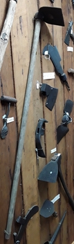 A steel curved and straight sided hoe with a wooden handle used for chopping into the ground.