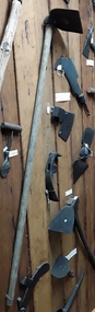 A steel curved and straight sided hoe with a wooden handle used for chopping into the ground.