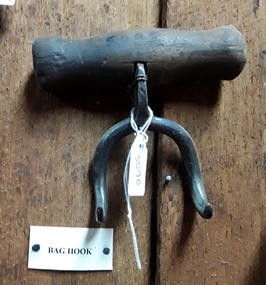 A small steel bag hook with two pointed hooks and a wooden handle.