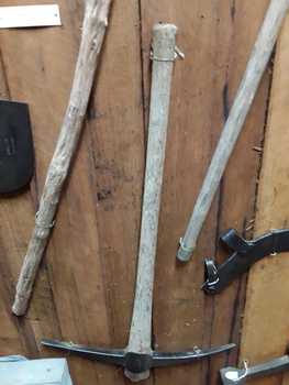 A two pointed steel handmade pick with a wooden handle used to break up soil.