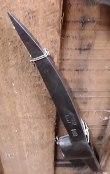 A small forged steel pick head with a point at one end and the other is squared off.