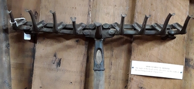 A hand used steel adjustable scarifier with a long wooden handle.