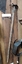 A metal hoe, rake combined scarifier or cultivator with a long wooden handle.