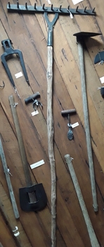 A handmade steel bush rake with a roghly hewn long wooden handle.