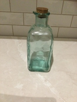 Green square based bottle with cork. Has pouring spout.