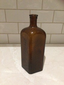 Brown glass whisky bottle with no lid or top.
