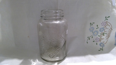 A screw-top clear glass jam jar with no lid.