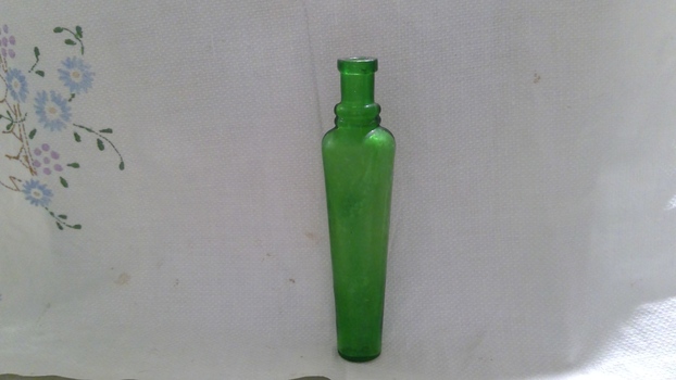 Green glass bottle with no lid or stopper.
