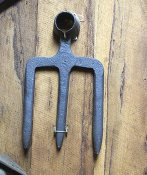 A thick forged steel three pronged fork hoe head made by a blacksmith. Handle is missing.