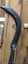A handmade slasher with a long wooden handle and a heavy sharp steel blade attached with a rivet to the handle. 