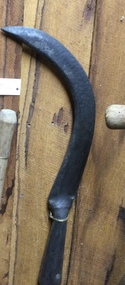 A handmade slasher with a long wooden handle and a heavy sharp steel blade attached with a rivet to the handle. 
