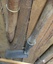 A hand slasher with a long wooden handle and a heavy sharp steel rectangular blade attached with rivets to the handle.