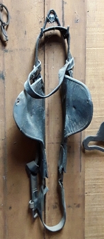 A pair of vintage leather horse winkers with metal rings and side leather buckles to strap it around the horse's head and eyes.