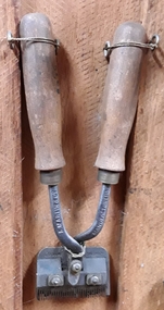 A pair of vintage hand horse clippers with two steel blades and steel handles with wooden grips attached.