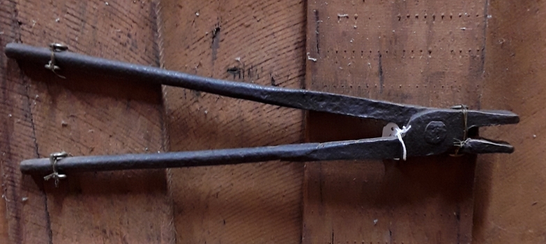 A pair of small vintage handmade blacksmith tongs with two handles  which are riveted together to form a hinge joint for the flat edged tongs.