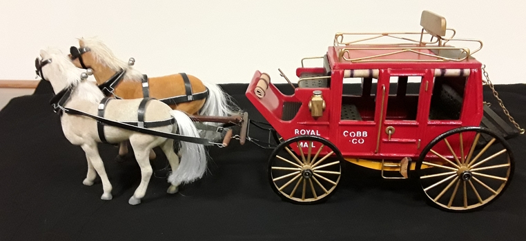 A model of a red Cobb and Co passenger coach with two horses from the 1800's.
