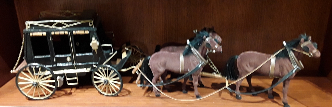 A model of a black enclosed coach with three brown horses used as transport in the 1800's in Victoria Australia.