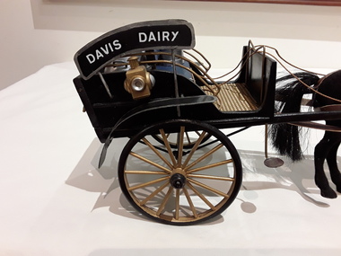 A model of a horse drawn black open Davis Dairy Buggy or Cart used to deliver milk in the late 1800's and early 1900's.