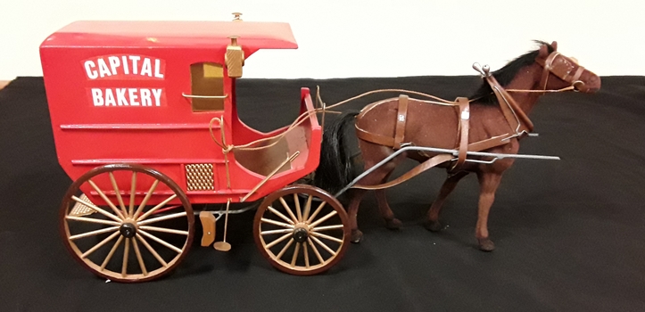 A model of a single horse drawn red enclosed Capital Bakery Cart which is a lightweight four wheeled one passenger horse drawn carriage.