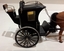 A model of an enclosed black buggy which is a two wheeled two passenger horse drawn carriage.