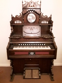 A highly decorated, delicate ornately carved wooden pump organ.
