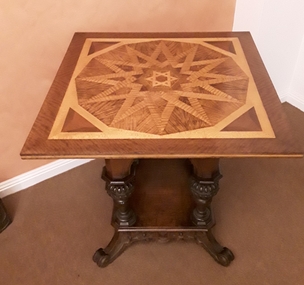 A handmade square wooden card table featuring an ornately patterned inlaid top of lighter coloured woods.