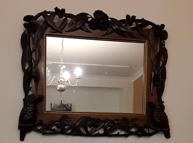 An elaborately carved wooden framed mirror with two carved kookaburras and Australian flora.
