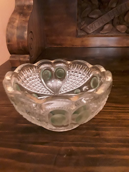 A small round cut glass decorative bowl with a green circular pattern and gold trim around the top scalloped edge.