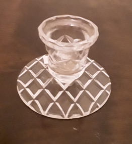 A small cut glass candle holder with a round base.