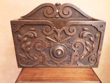 A highly decorated wooden hand carved rectangular magazine holder. The back of it is plain.