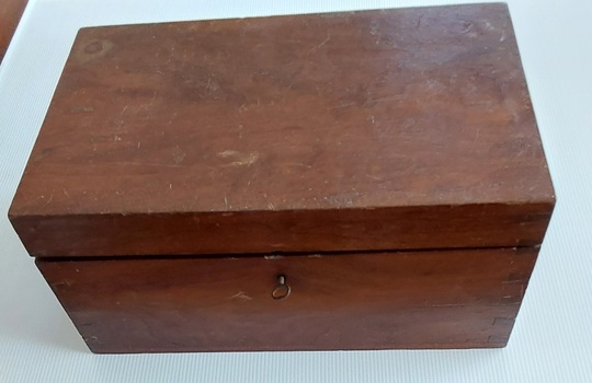 A brown varnished rectangular wooden lidded Sewing Box with a lift out top section filled with sewing items.
