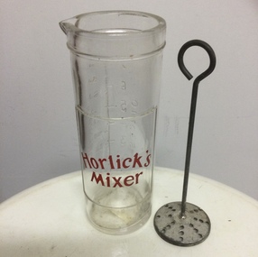 A glass Horlick’s medicinal mixing jar with a red Horlick’s Mixer label on the front and measures on thr back. 