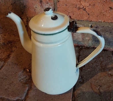 A tall cream enamel coffee pot with a goose neck spout, handle, green trim around the top.