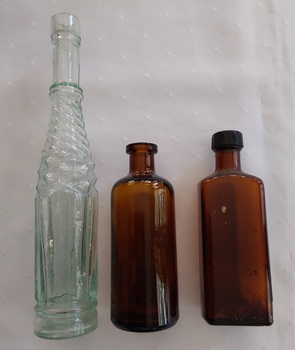 Three varying sized glass bottles: one clear and two brown glass. 