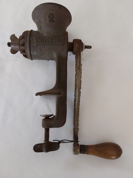 A cast iron mincer with a wooden handle attached to the long cast iron handle.