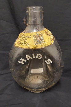 A clear glass squat Old Blended Scotch Whisky bottle with thin black wire wrapped around it.