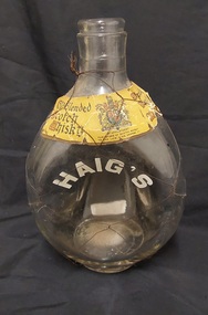 A clear glass squat Old Blended Scotch Whisky bottle with thin black wire wrapped around it.