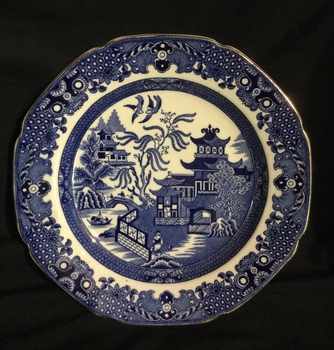 A blue and white Willow Pattern scalloped edged dessert plate with a fine gold line around the outer edge.
