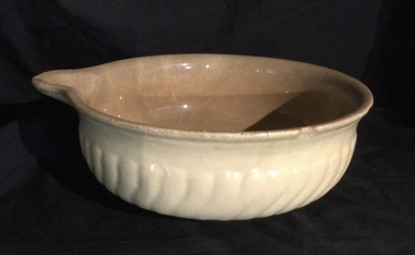 A vintage medium sized cream coloured stoneware mixing bowl with a pouring lip for cooking.ring lip.