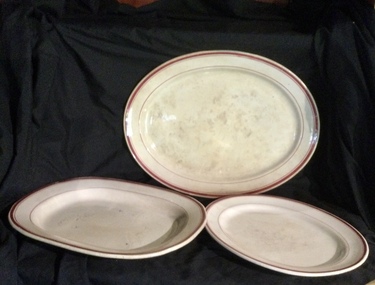 Two oval vintage and one rectangular white ceramic serving platters with three red stripes around the rim.