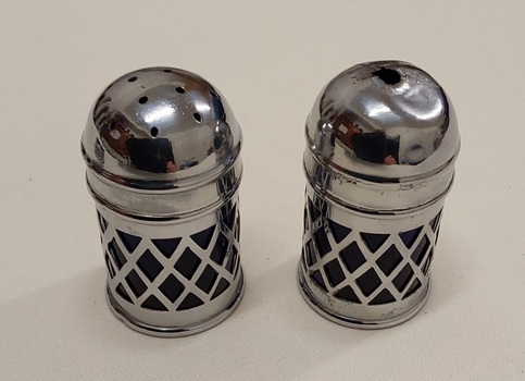 A pair of small silver plate salt and pepper shakers with a basket weave outer container and a cobalt blue glass insert. 